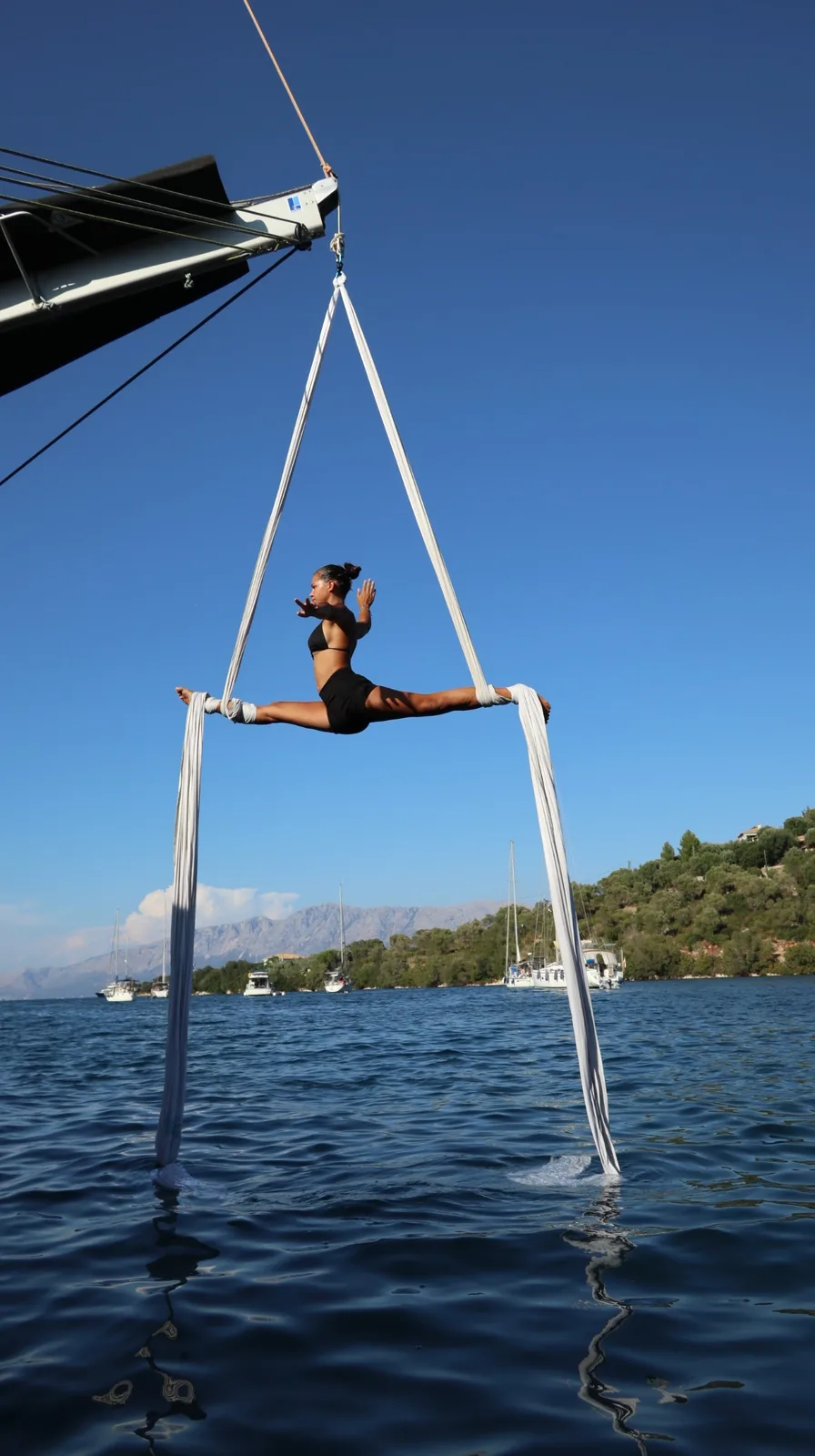 Split held on white silks rigged from a boom, coastline in the background
